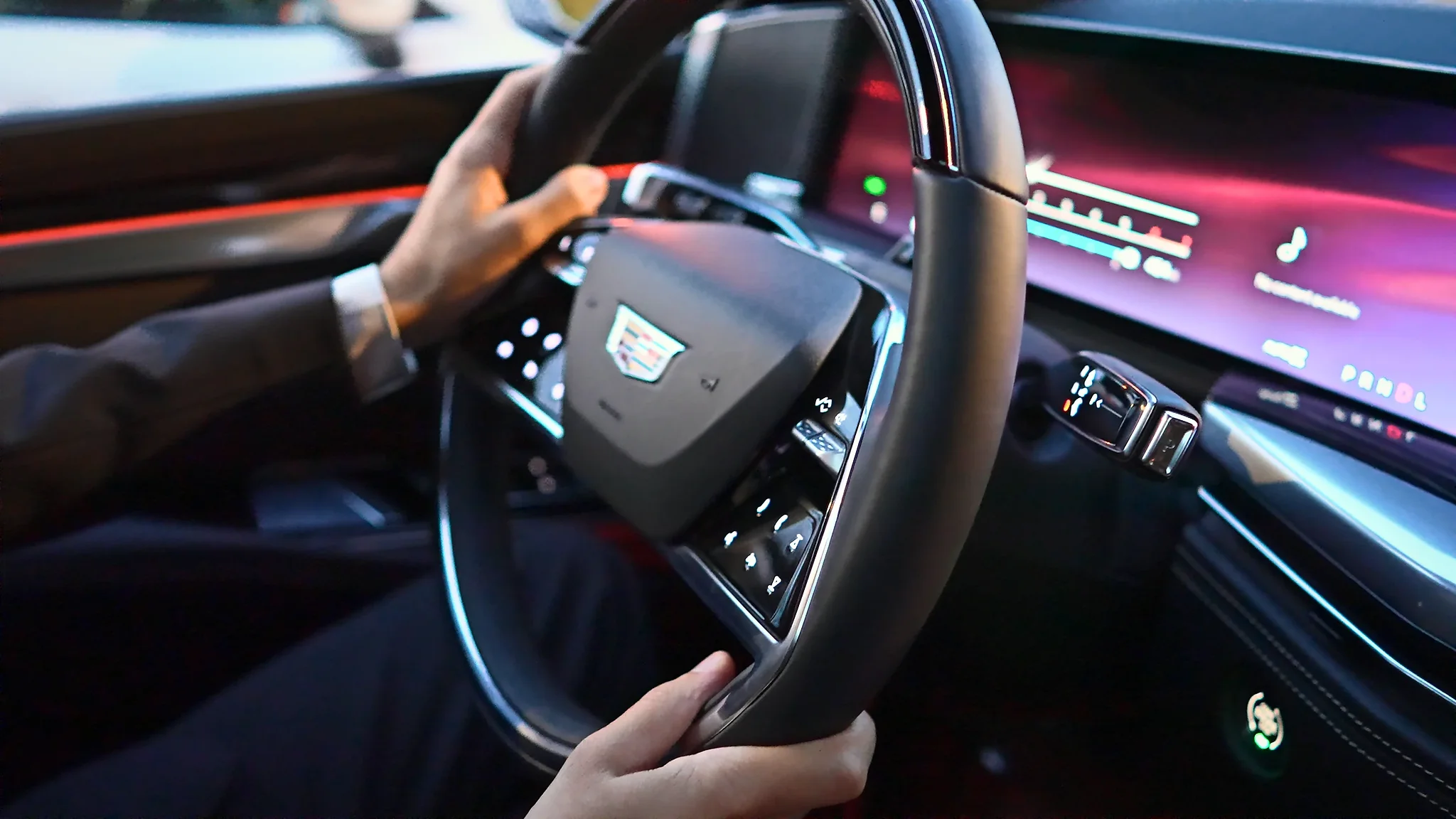 A chauffeur's hands on the wheel of a Cadillac Escalade ESV with the dashboard lit