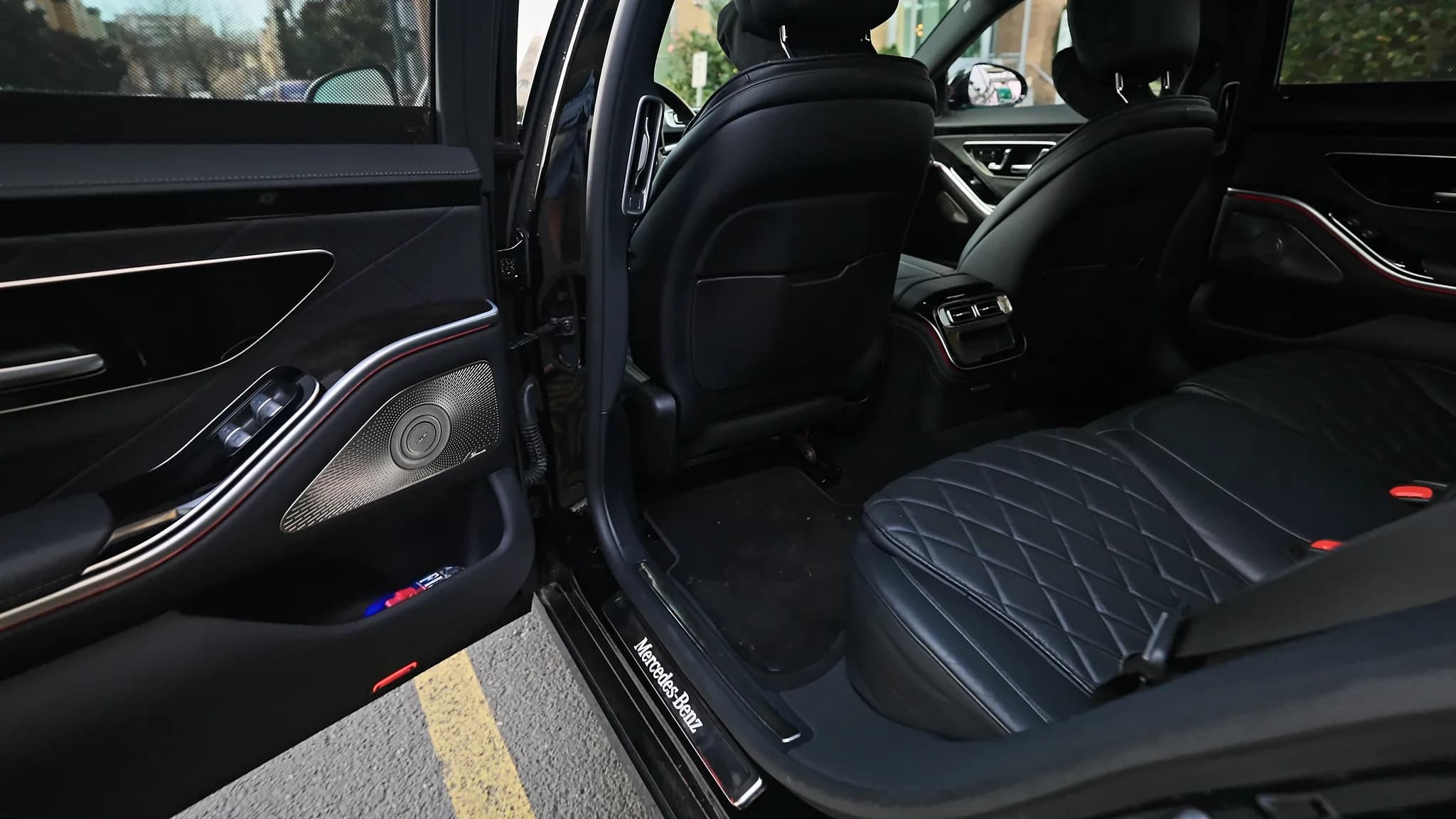 Rear cabin of a black chauffeured sedan with quilted leather seats