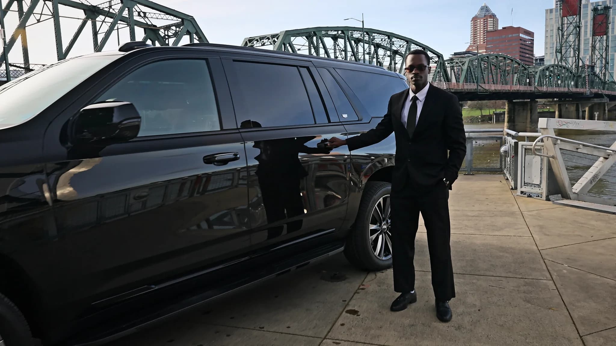 Chauffeur presenting the open rear door of a Cadillac Escalade ESV on the Portland waterfront