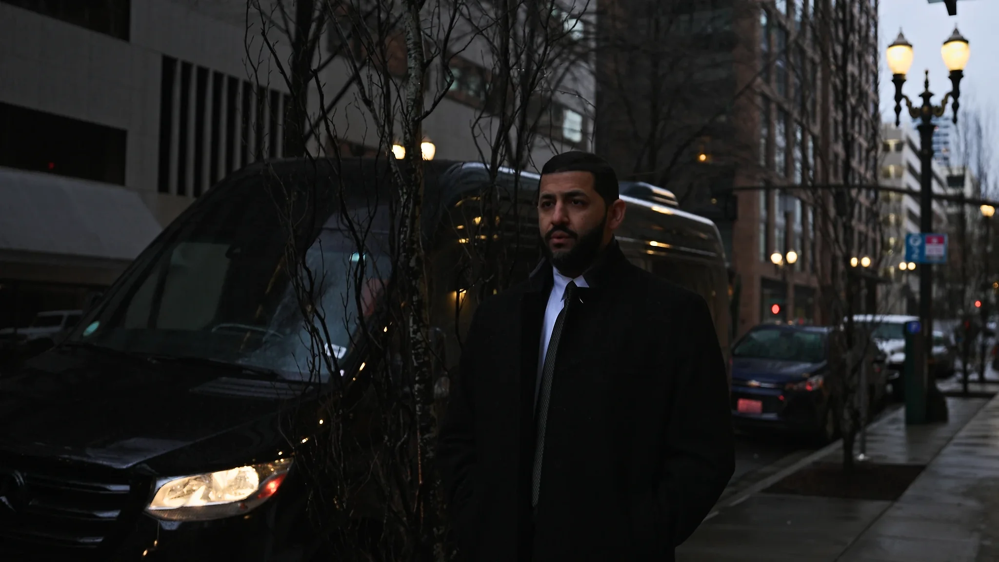 Chauffeur beside the Sprinter Jet Limousine on a wet downtown Portland street