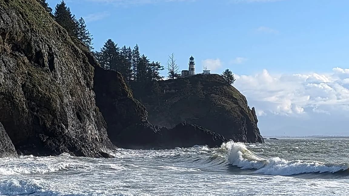 Rocky Pacific headland with a lighthouse and breaking surf — coast leg of a city and coast tour