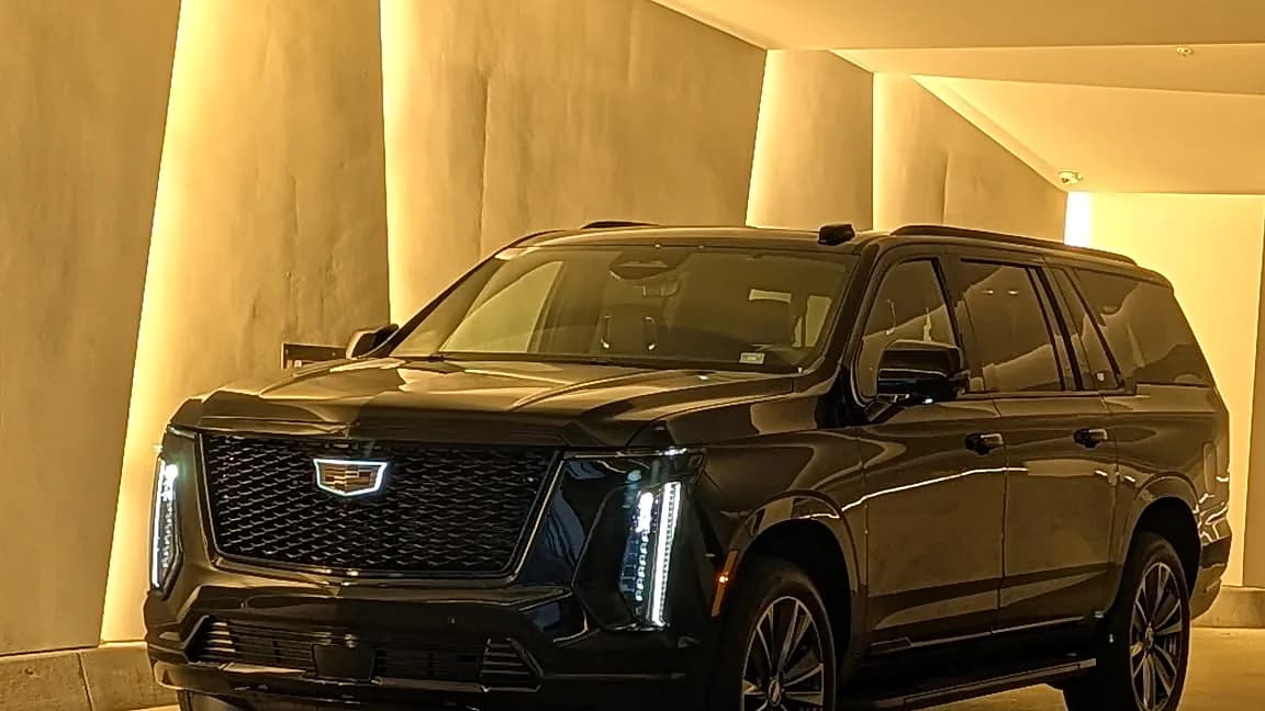Black Cadillac Escalade under a warmly lit covered portico — airport car service arrival