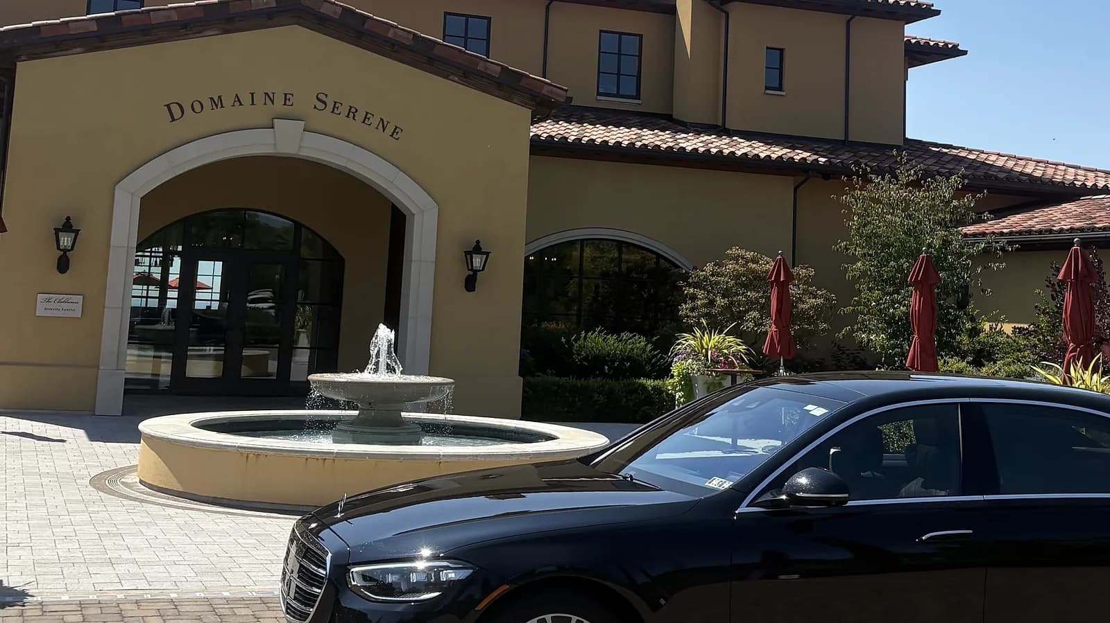 Black chauffeured sedan by the fountain at the Domaine Serene tasting room entrance — Dundee Hills wine tour