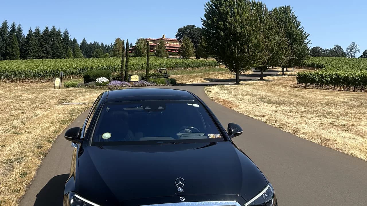 Black chauffeured sedan on a sunlit vineyard road in summer — Oregon wine tour