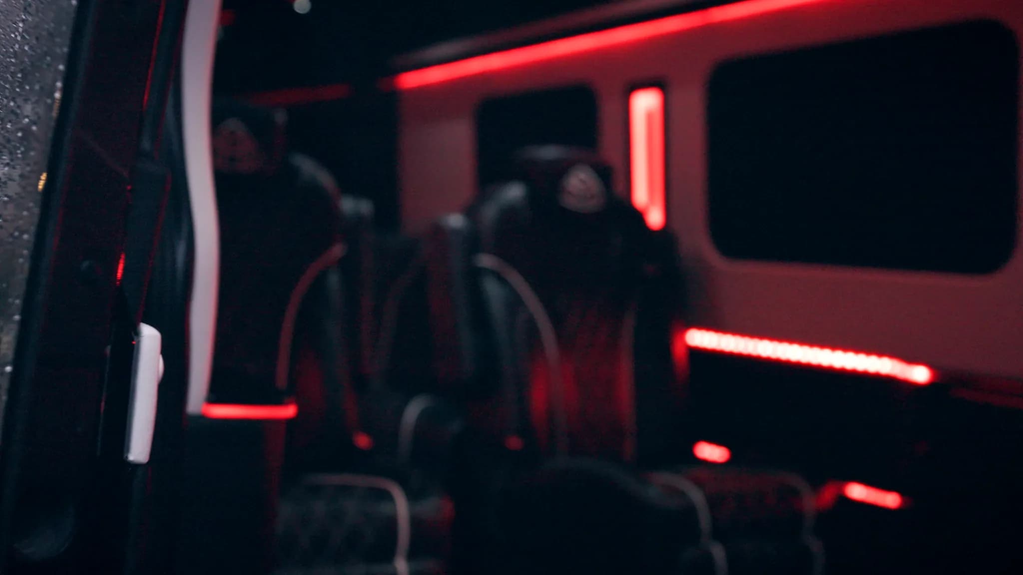 Sprinter limousine cabin lit with red accent lighting, seen through the open door