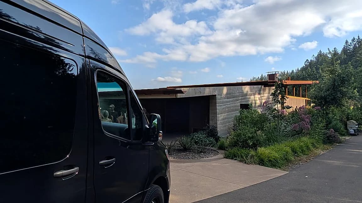 Mercedes-Benz Sprinter parked outside a modern winery under blue sky — wine tour estate stop