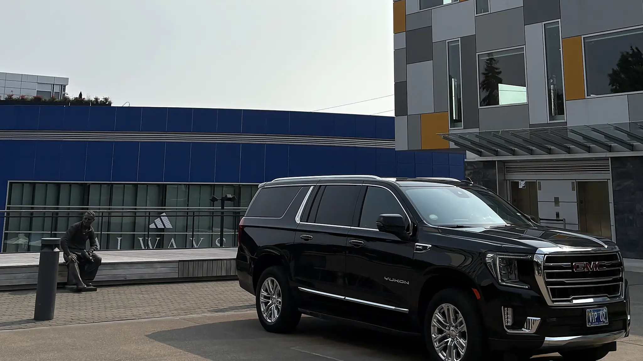 Black chauffeured SUV parked outside a modern office building — executive car service pickup