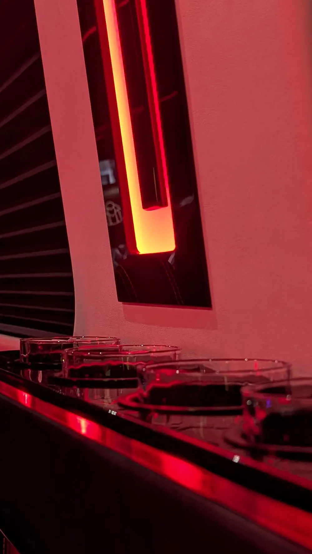 Glass tumblers set on the VIP Lounge Sprinter's gloss-black bar table beside a lit window accent panel under red LED
